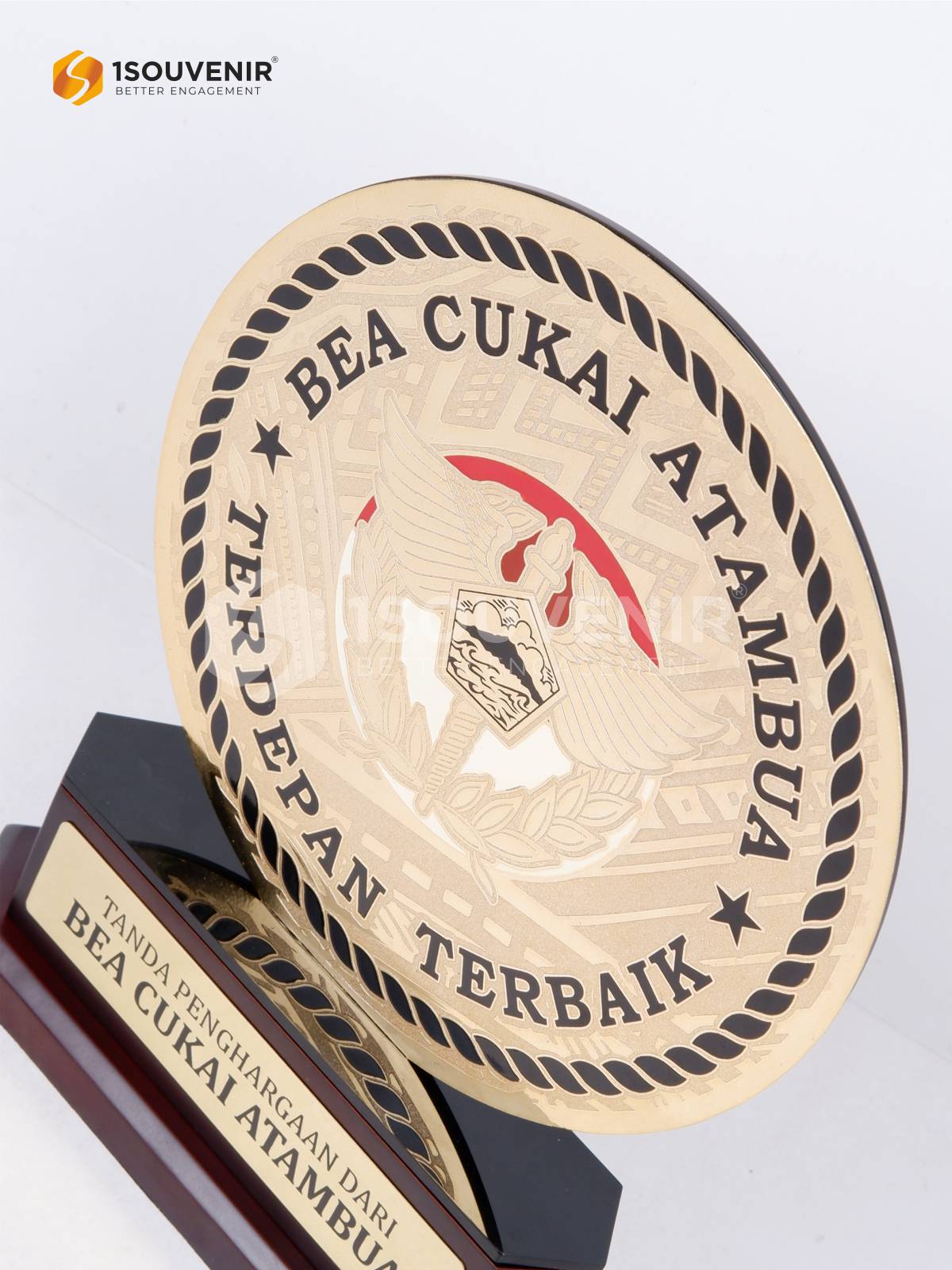 Detail panel bundar plakat dengan ornamen tali pilin hitam dan aksen merah di belakang lambang bersayap